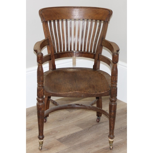 10 - An early 20th century oak armchair or desk chair on brass castors, approx 60cm wide x 55cm deep x 91... 