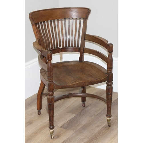 10 - An early 20th century oak armchair or desk chair on brass castors, approx 60cm wide x 55cm deep x 91... 
