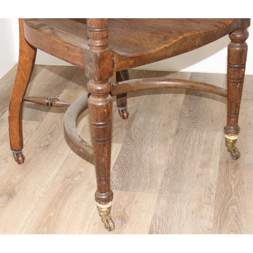 10 - An early 20th century oak armchair or desk chair on brass castors, approx 60cm wide x 55cm deep x 91... 