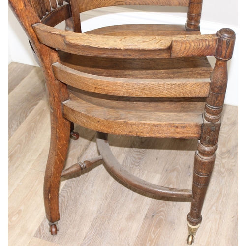 10 - An early 20th century oak armchair or desk chair on brass castors, approx 60cm wide x 55cm deep x 91... 