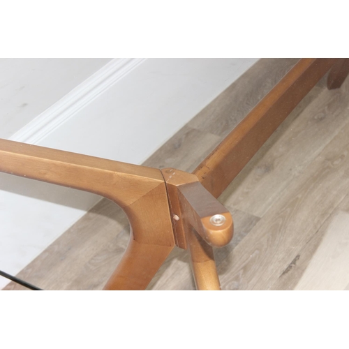 29 - A retro style glass topped dining table with shaped wooden base, approx 181cm x 100cm x 75cm