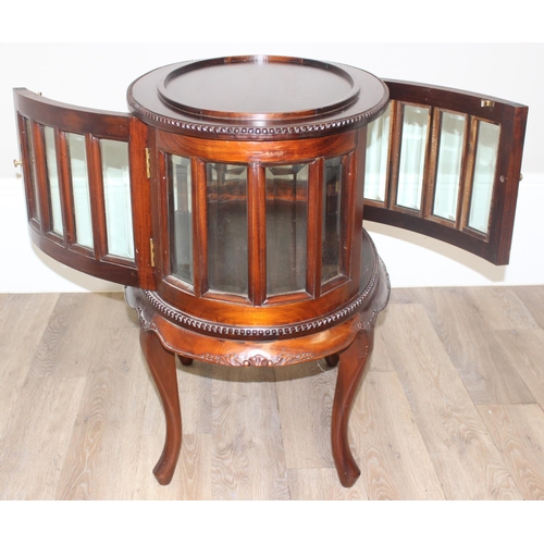 25 - A 20th century mahogany drinks cabinet of oval form with tray top above a glazed door and sides on s... 