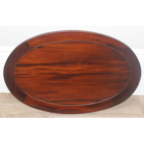 25 - A 20th century mahogany drinks cabinet of oval form with tray top above a glazed door and sides on s... 