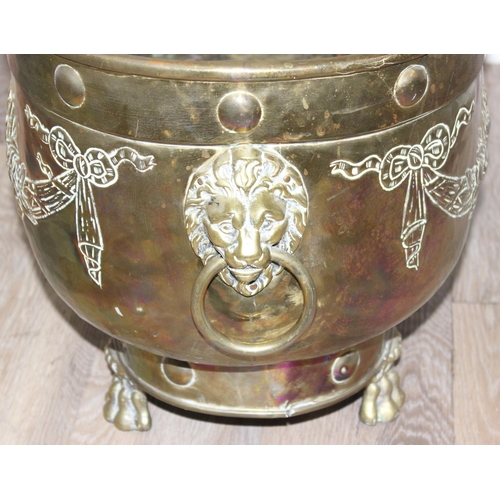 29 - A large brass planter with embossed floral design, lion head handles and paw feet, likely early 20th... 