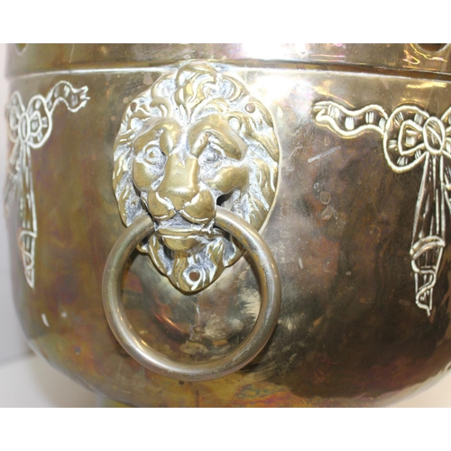 29 - A large brass planter with embossed floral design, lion head handles and paw feet, likely early 20th... 