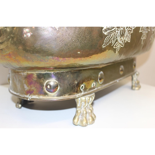 29 - A large brass planter with embossed floral design, lion head handles and paw feet, likely early 20th... 