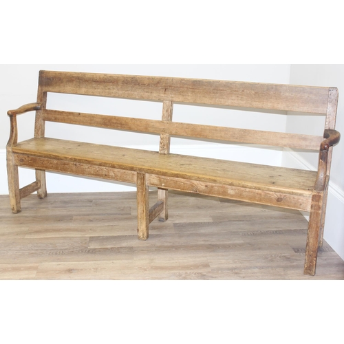 3 - An antique rustic pine bench with shaped arms and high back, likely 19th century, approx 205cm wide ... 