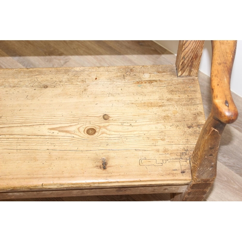 3 - An antique rustic pine bench with shaped arms and high back, likely 19th century, approx 205cm wide ... 