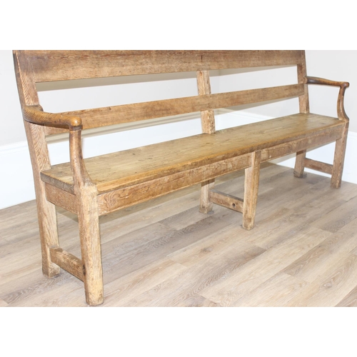 3 - An antique rustic pine bench with shaped arms and high back, likely 19th century, approx 205cm wide ... 