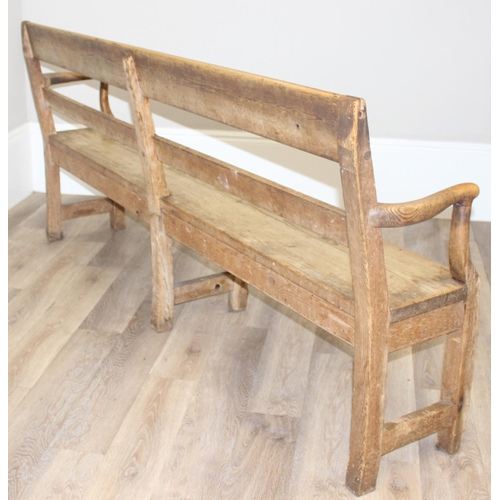 3 - An antique rustic pine bench with shaped arms and high back, likely 19th century, approx 205cm wide ... 