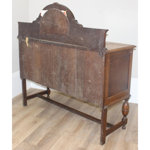 32 - An early 20th century oak sideboard with 2 drawers over a deep central drawer flanked by 2 doors, wi... 