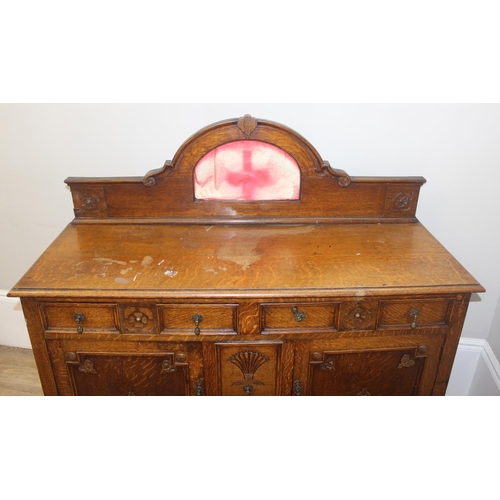 32 - An early 20th century oak sideboard with 2 drawers over a deep central drawer flanked by 2 doors, wi... 