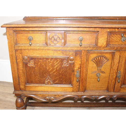 32 - An early 20th century oak sideboard with 2 drawers over a deep central drawer flanked by 2 doors, wi... 