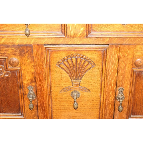 32 - An early 20th century oak sideboard with 2 drawers over a deep central drawer flanked by 2 doors, wi... 