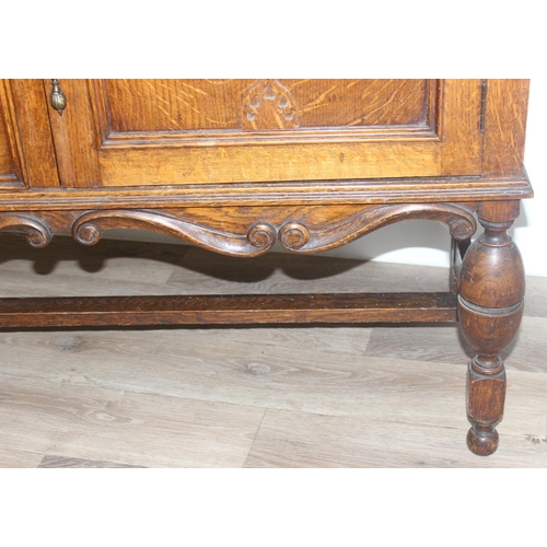 32 - An early 20th century oak sideboard with 2 drawers over a deep central drawer flanked by 2 doors, wi... 