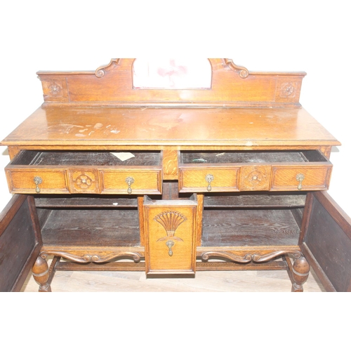 32 - An early 20th century oak sideboard with 2 drawers over a deep central drawer flanked by 2 doors, wi... 