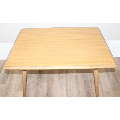 51 - A retro Ercol dining table, blonde finish with paper rack under, later stuck on Formica top, approx ... 