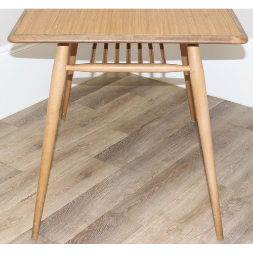 51 - A retro Ercol dining table, blonde finish with paper rack under, later stuck on Formica top, approx ... 