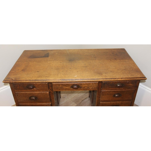 57 - An early 20th century oak desk with 9 drawers with brass cup handles, approx 130cm wide x 63cm deep ... 