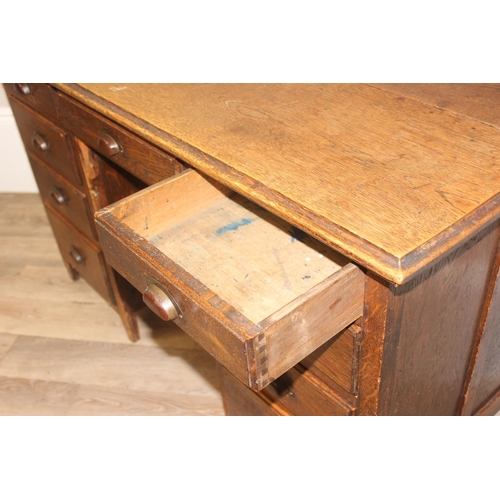 57 - An early 20th century oak desk with 9 drawers with brass cup handles, approx 130cm wide x 63cm deep ... 