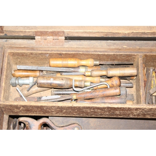 719 - A large vintage stained pine tool box with extensive contents to inc a number of wooden planes, saws... 