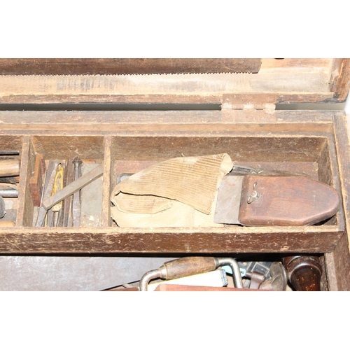 719 - A large vintage stained pine tool box with extensive contents to inc a number of wooden planes, saws... 