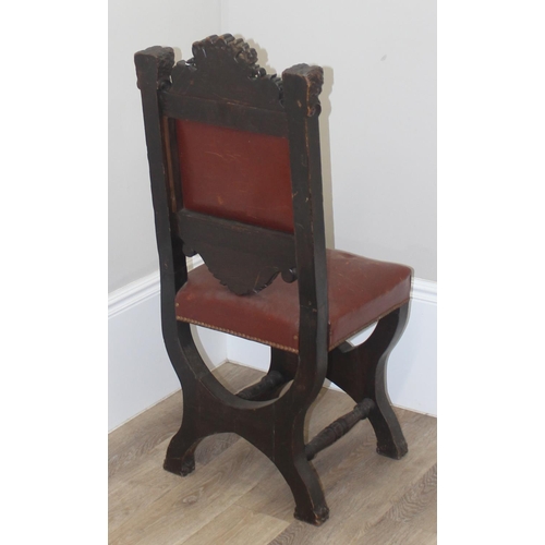 135 - A 17th century style carved oak chair with leather seat and back, the frame profusely carved with va... 