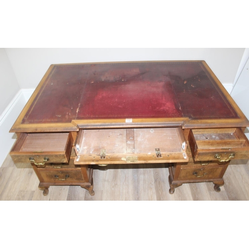 150 - An early 20th century Walnut desk by Hamptons of London, a walnut veneered 9 drawer desk with Georgi... 