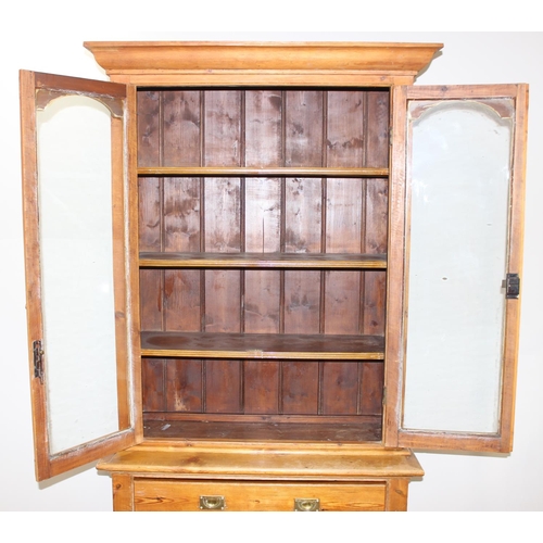 153 - An antique pitch pine dresser of slim proportions, the top with glazed doors, over a single drawer w... 