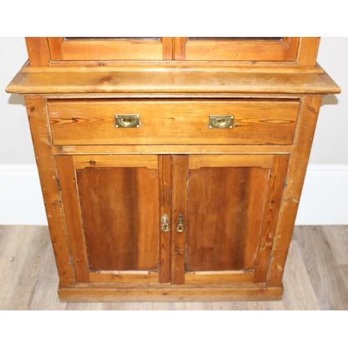 153 - An antique pitch pine dresser of slim proportions, the top with glazed doors, over a single drawer w... 