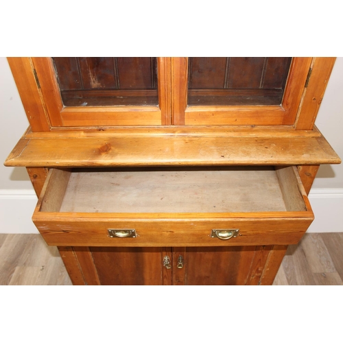 153 - An antique pitch pine dresser of slim proportions, the top with glazed doors, over a single drawer w... 