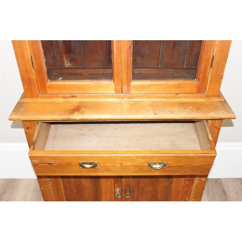 153 - An antique pitch pine dresser of slim proportions, the top with glazed doors, over a single drawer w... 