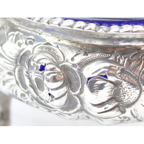 1048 - A pair of early Victorian cast silver salts with floral and lion head decoration, with blue glass li... 