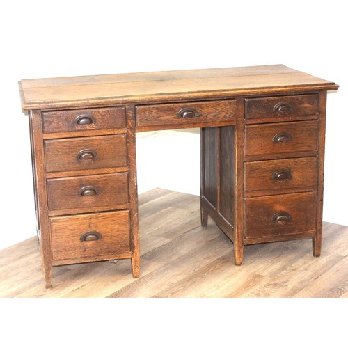 57 - An early 20th century oak desk with 9 drawers with brass cup handles, approx 130cm wide x 63cm deep ... 