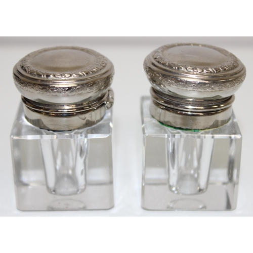 1039 - A vintage desk set comprising of a pair of glass inkwells and a desk blotter with silver plated moun... 