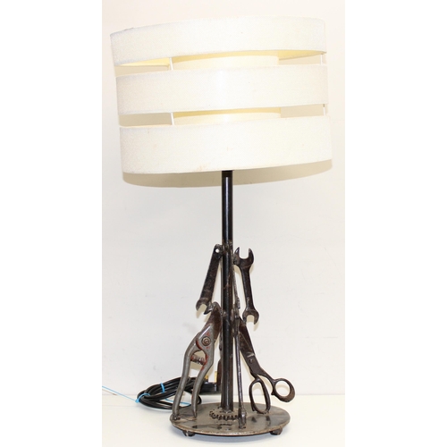 237 - A vintage table lamp with shade, the base formed from a sprocket and welded tools to inc spanners an... 