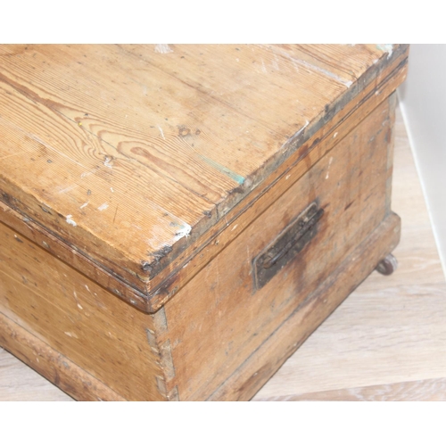 49 - Vintage pine wooden trunk on wheels with wrought iron handles and hinged lid, approx 77cm W x 44cm D... 