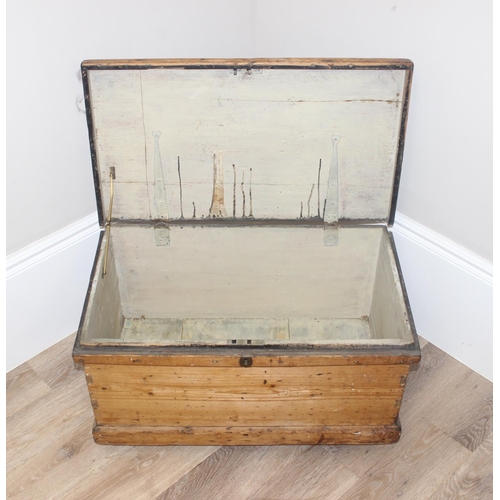 49 - Vintage pine wooden trunk on wheels with wrought iron handles and hinged lid, approx 77cm W x 44cm D... 