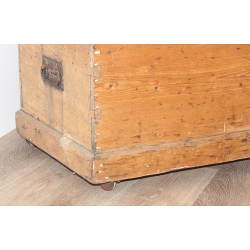 49 - Vintage pine wooden trunk on wheels with wrought iron handles and hinged lid, approx 77cm W x 44cm D... 