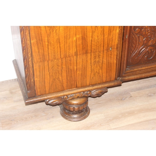 15 - A large 17th century style heavily carved oak sideboard with a central carved cupboard flanked by 2 ... 