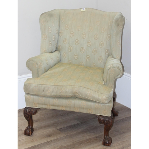 48 - A Georgian style wingback armchair with carved ball and claw feet and light green striped and patter... 