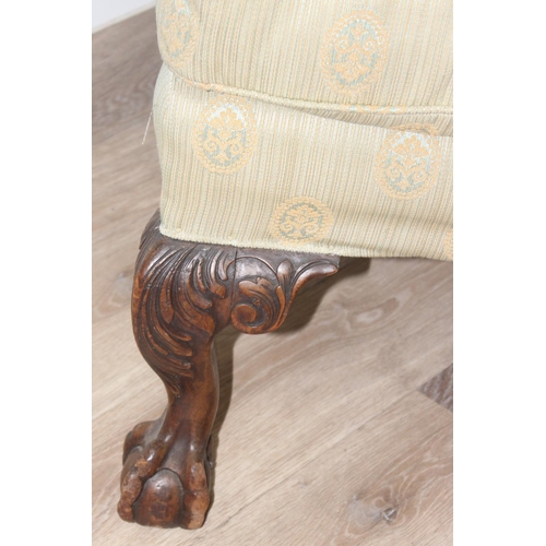 48 - A Georgian style wingback armchair with carved ball and claw feet and light green striped and patter... 