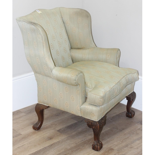 48 - A Georgian style wingback armchair with carved ball and claw feet and light green striped and patter... 