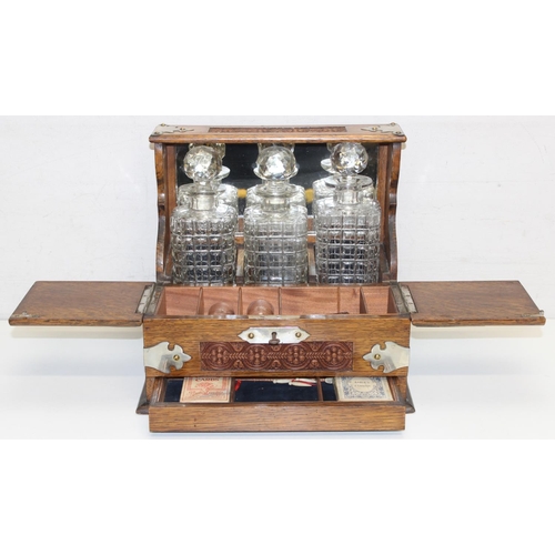 1537 - A 19th century oak 3 bottle tantalus with secret compartment, the body with carved details, approx 3... 