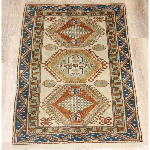 205 - A vintage hand knotted beige ground rug, likely Caucasian in origin, approx 134cm x 95cm