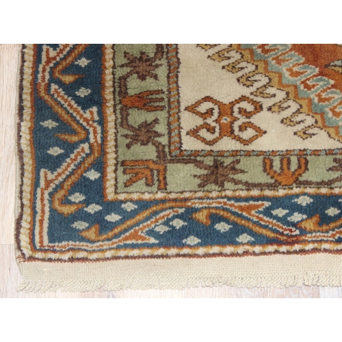 205 - A vintage hand knotted beige ground rug, likely Caucasian in origin, approx 134cm x 95cm