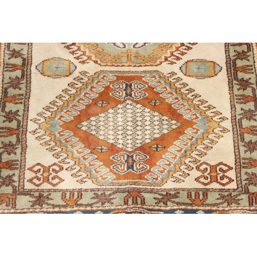 205 - A vintage hand knotted beige ground rug, likely Caucasian in origin, approx 134cm x 95cm