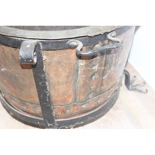 149 - A Victorian copper boiler with riveted join presented in a vintage blacksmith made wrought iron stan... 