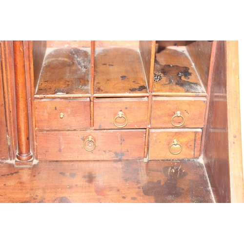 129 - A Georgian mahogany bureau with fitted interior, 4 long drawers with brass drop handles and bracket ... 