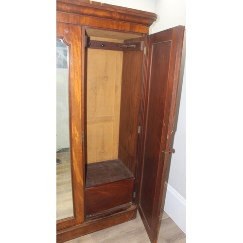 60 - A Victorian mahogany triple wardrobe press, the mirror and panel doors enclosing 4 trays, 2 over 2 d... 